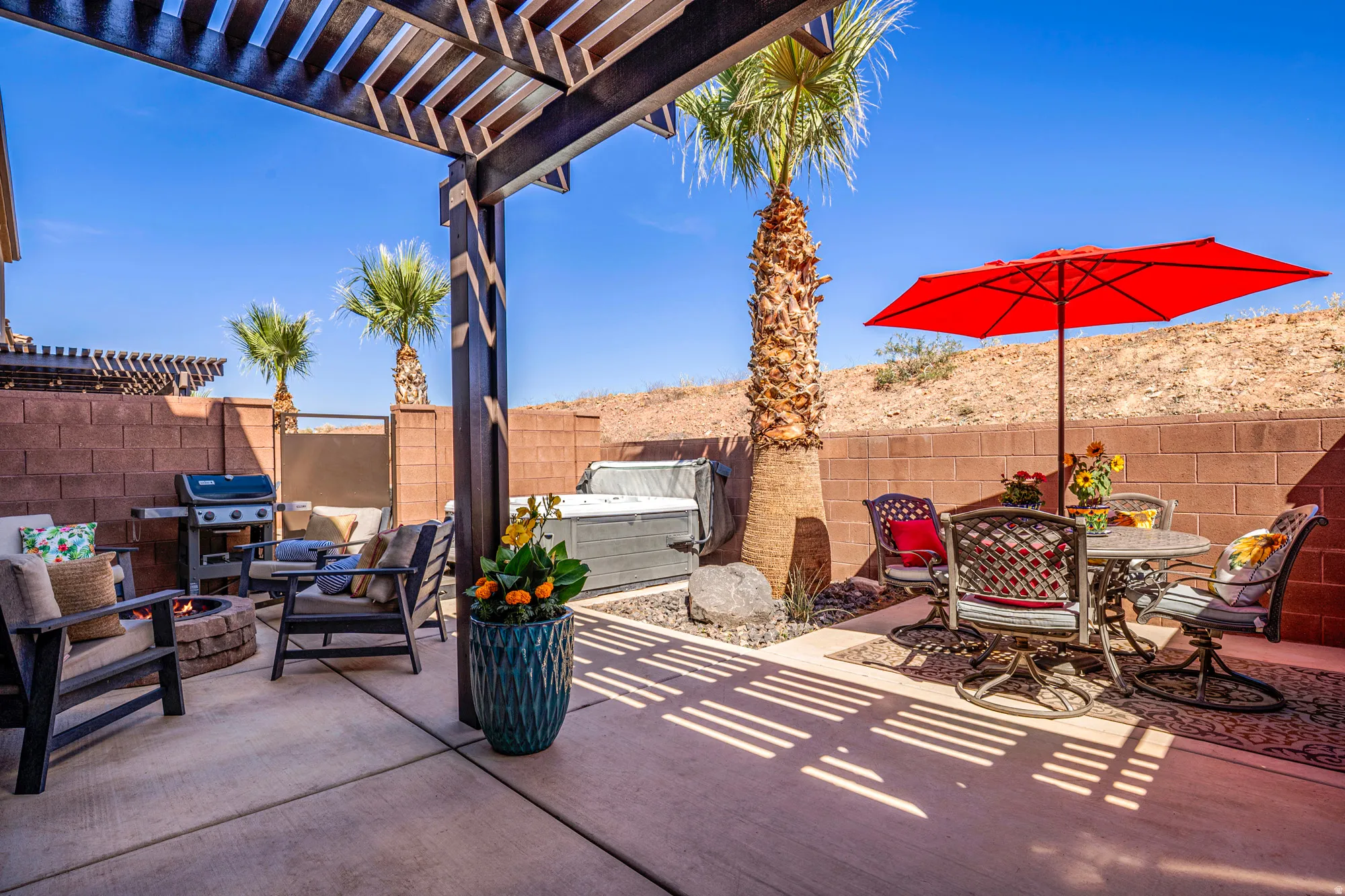 Expansive concrete patio featuring a dark wood pergola, built-in hot tub, and a fire pit