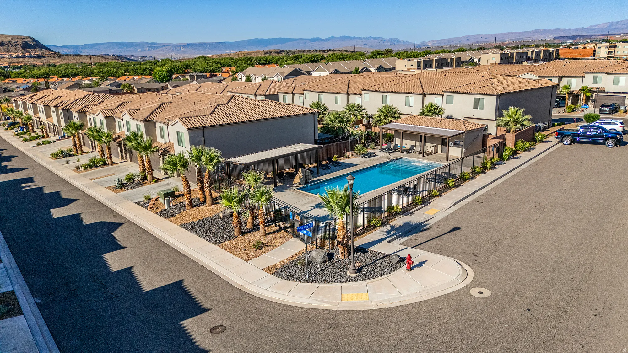 Community pool with an integrated covered patio, surrounded by a metal fence