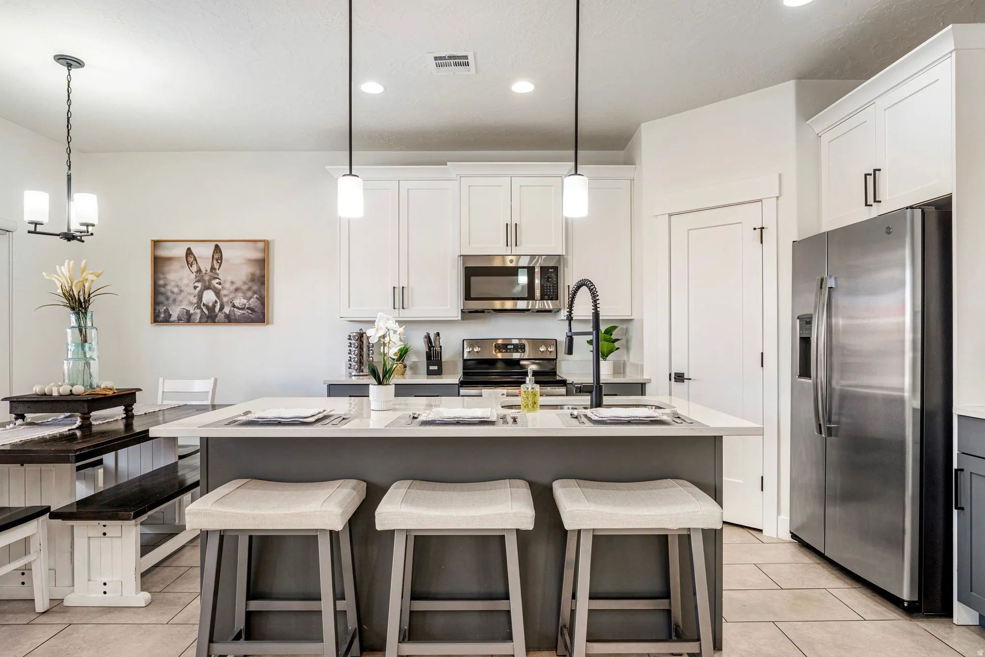 Kitchen featuring a central island with countertop seating, white shaker-style cabinetry, stainless steel appliances, and tile flooring