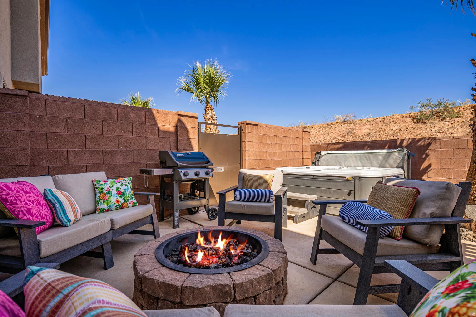 Private outdoor patio featuring a stone fire pit, built-in hot tub, and a gas grill