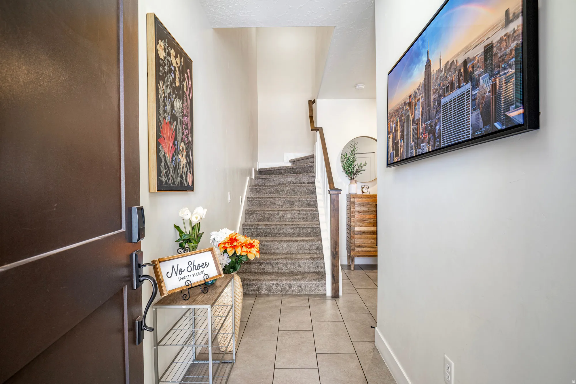 Inviting entryway featuring tile flooring and a carpeted staircase with wood handrails