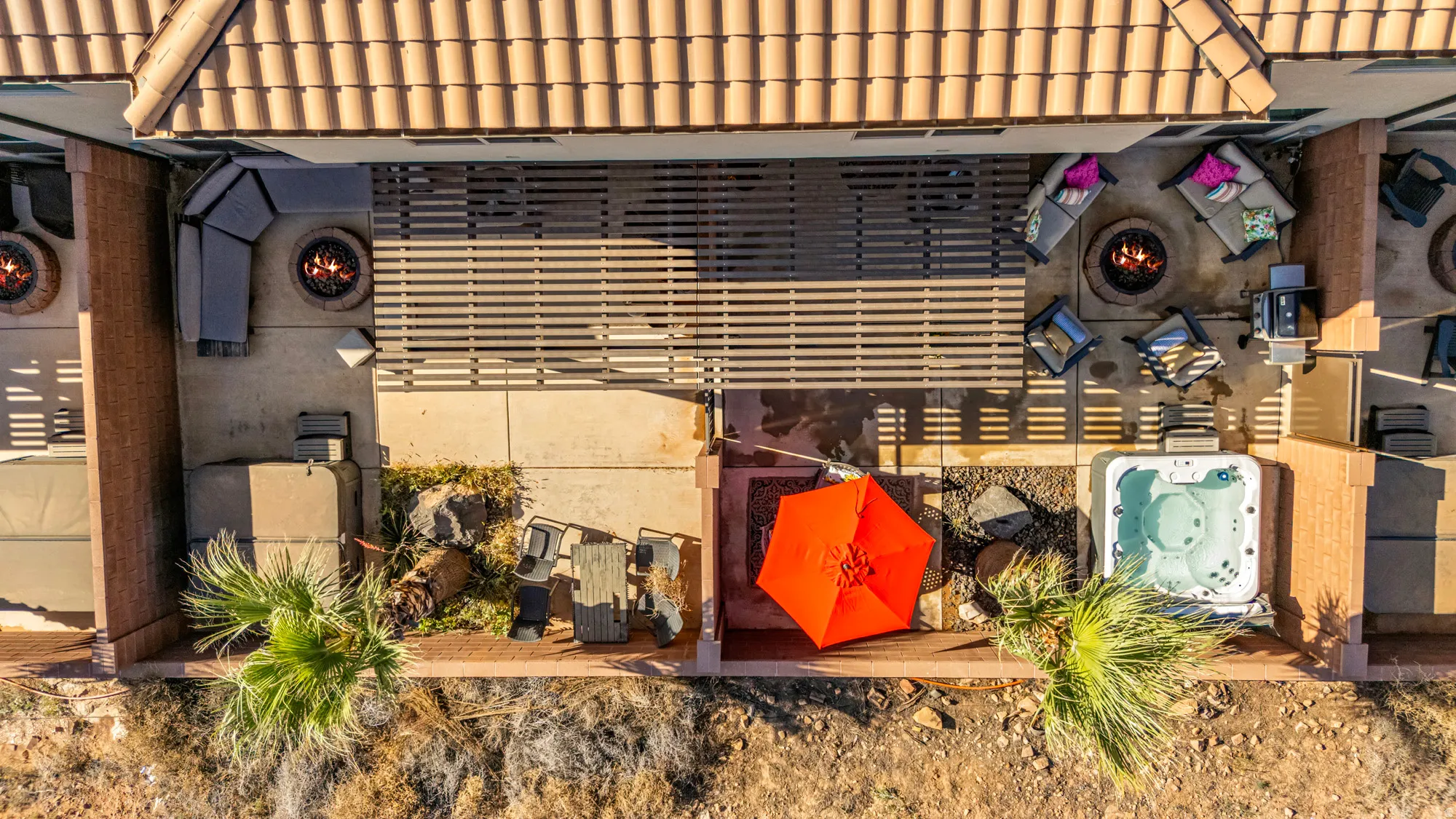 Expansive patio area featuring a built-in spa, two fire pits, a covered pergola, and desert landscaping