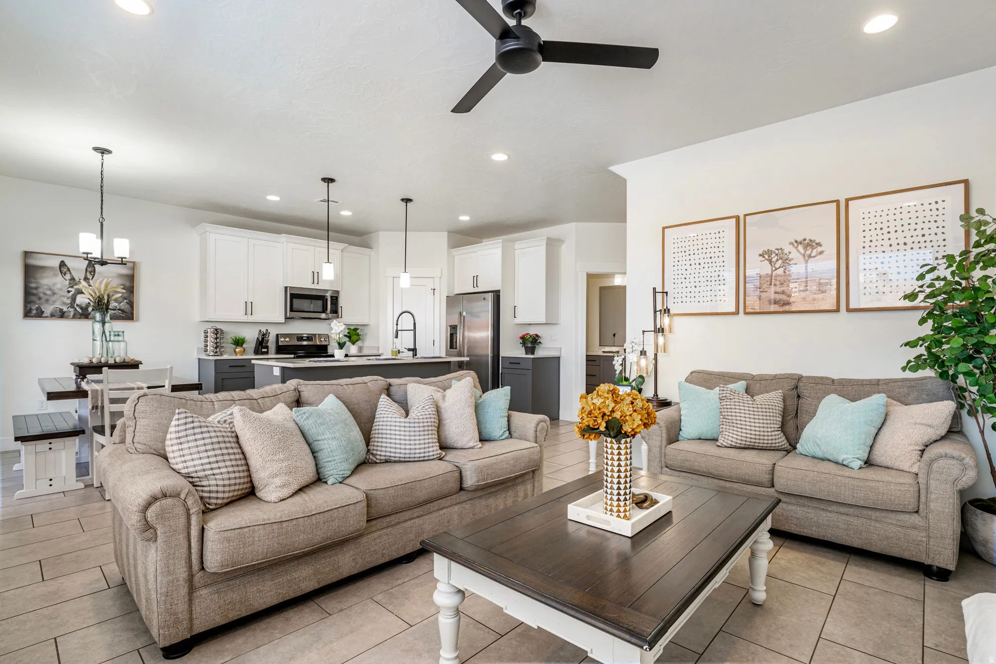 Open-concept living area featuring wood-finish tile flooring, a dark-toned ceiling fan with integrated lighting, and recessed ceiling lights