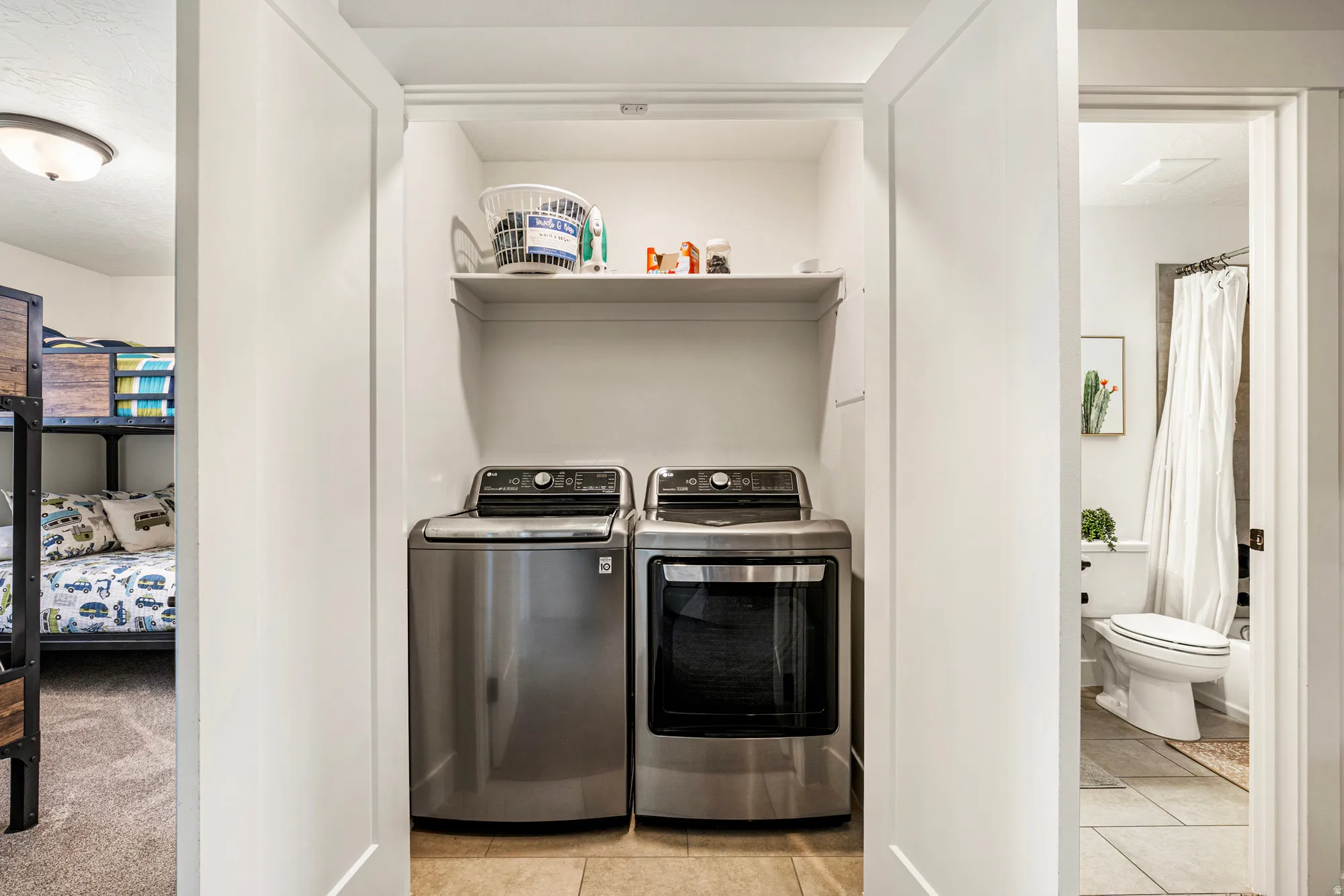 Dedicated laundry closet featuring a built-in shelf and tile flooring
