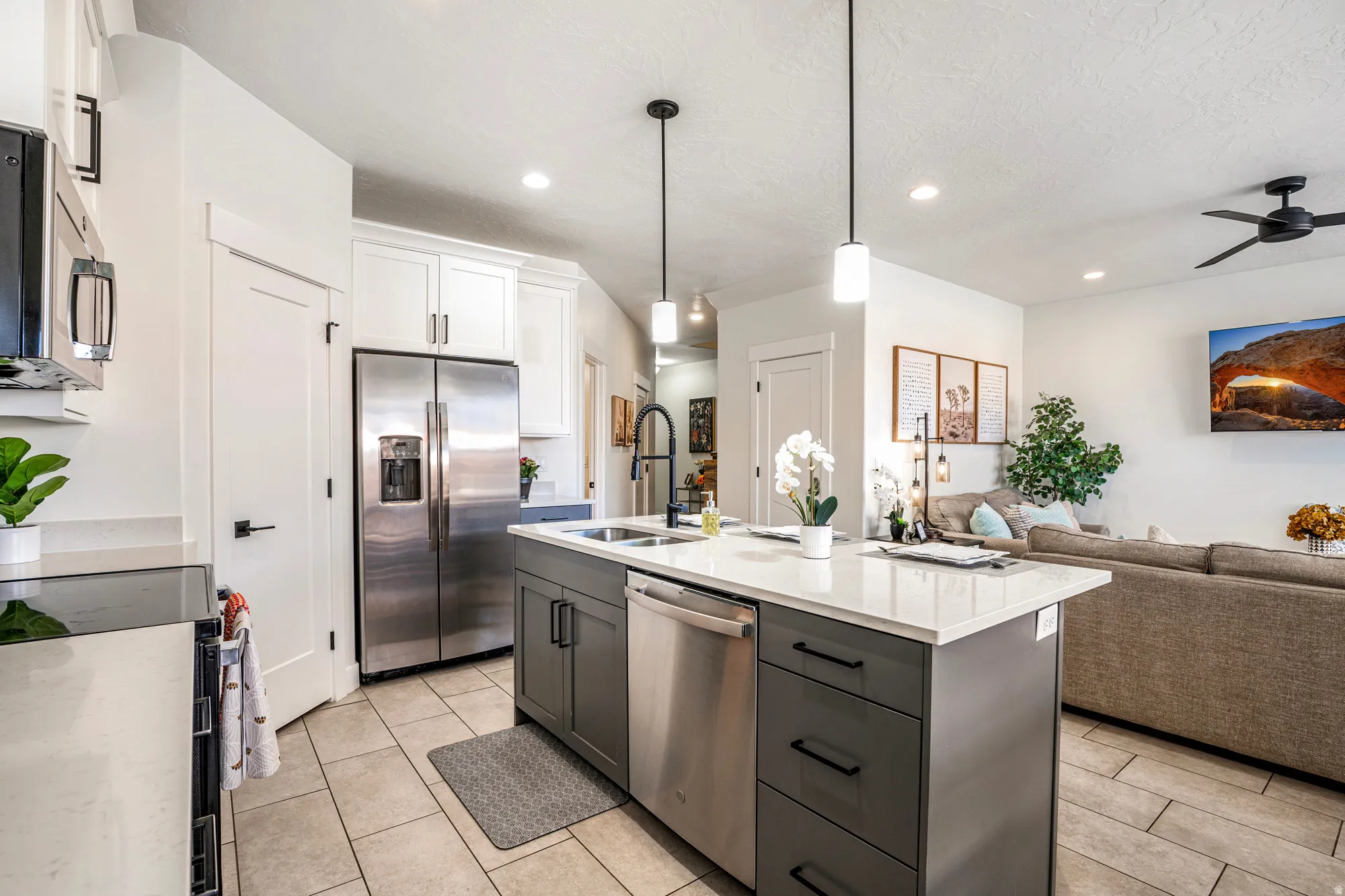 Kitchen island featuring a white countertop, an undermount sink with a black faucet, and pendant lighting