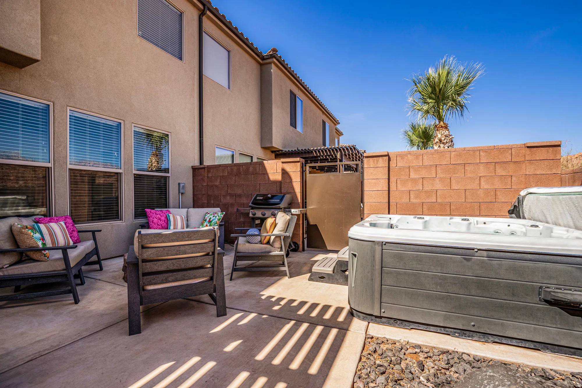 Concrete patio featuring a privacy wall, a built-in spa, and an attached pergola structure