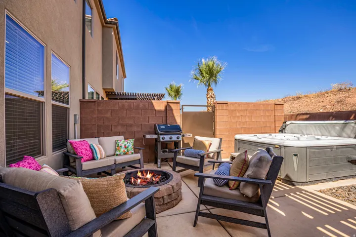 Outdoor patio featuring a built-in stone fire pit, a hot tub, concrete paver flooring, and a privacy wall