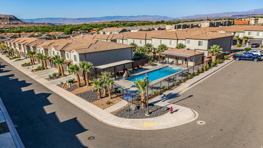 Community pool with an integrated covered patio, surrounded by a metal fence