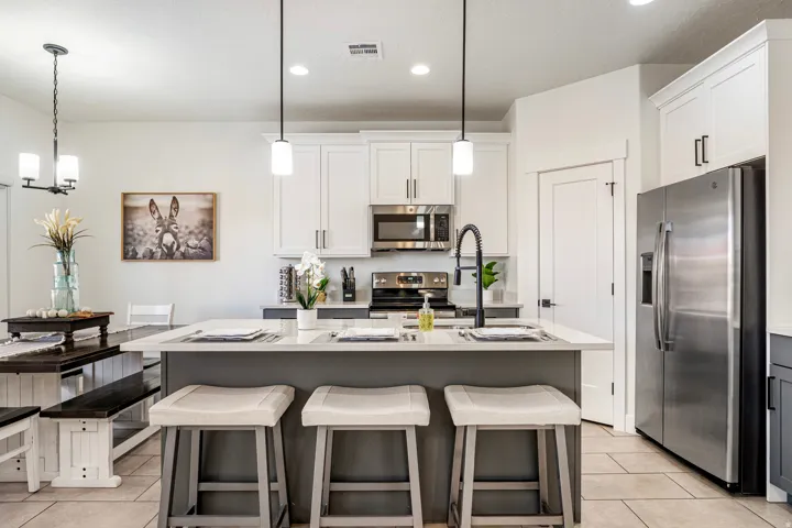 Kitchen featuring a central island with countertop seating, white shaker-style cabinetry, stainless steel appliances, and tile flooring