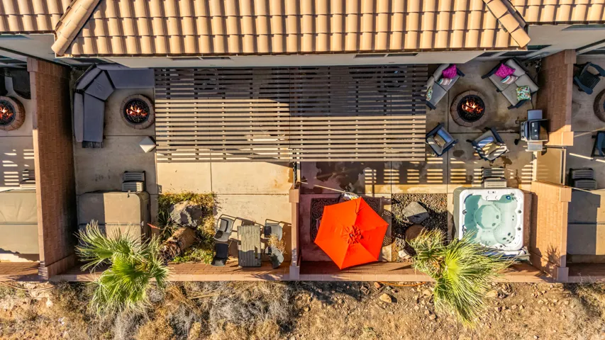 Expansive patio area featuring a built-in spa, two fire pits, a covered pergola, and desert landscaping