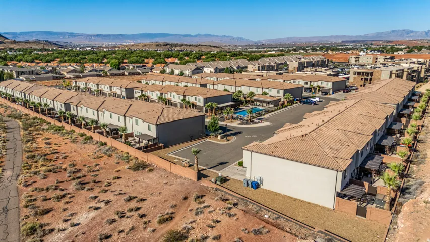 Aerial perspective of a multi-unit residential community featuring uniform tan-tiled roofs, light-colored exteriors, and private patios