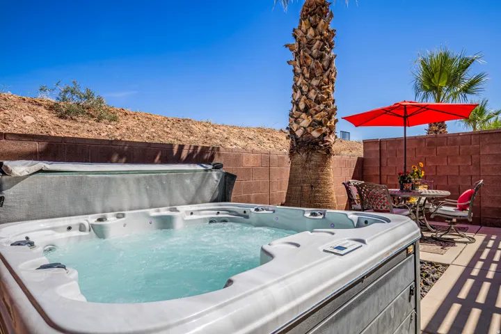 Outdoor patio featuring a built-in spa, concrete paver flooring, mature palm trees, and privacy block walls