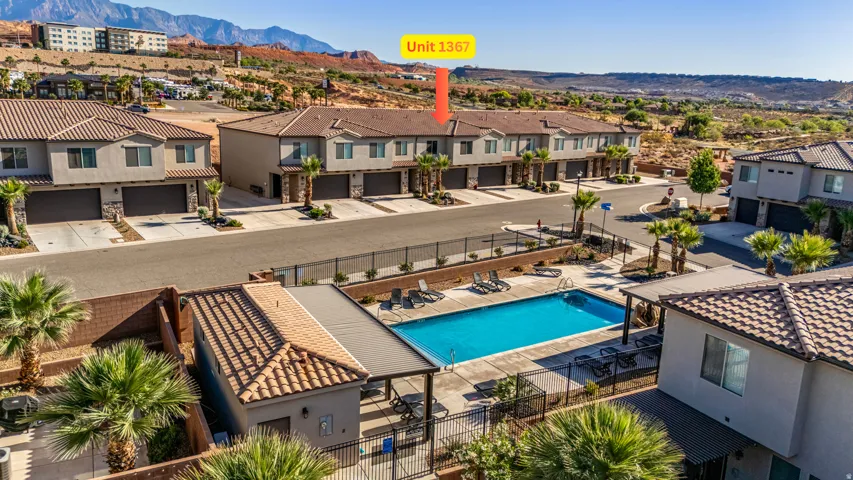 Community swimming pool with surrounding lounge seating, adjacent to a multi-unit residential building