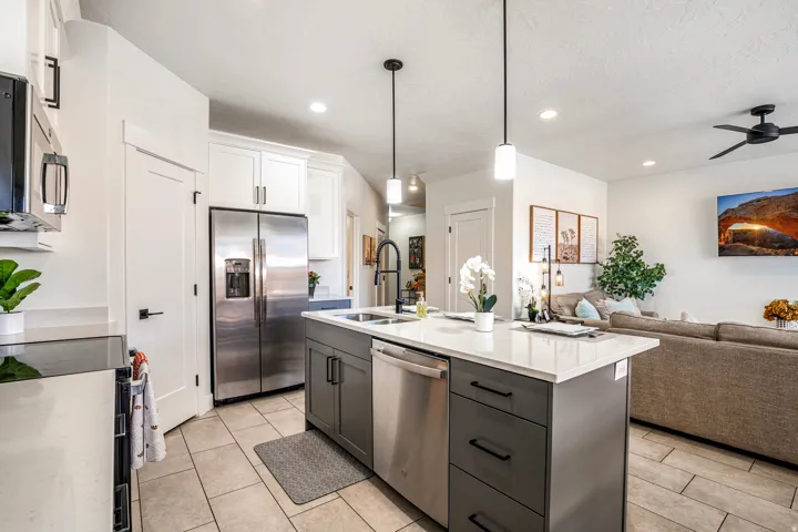 Kitchen island featuring a white countertop, an undermount sink with a black faucet, and pendant lighting