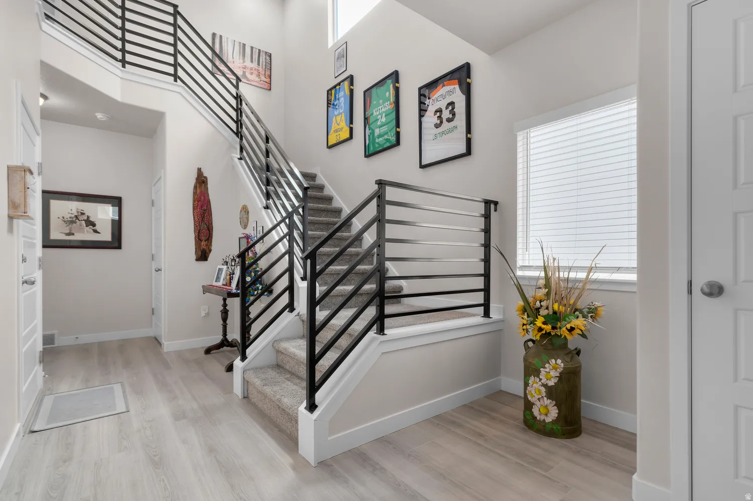 Two-story entryway featuring modern horizontal metal railings and light wood-finish flooring