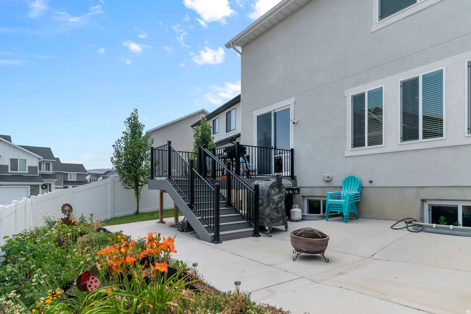 Outdoor patio space featuring a multi-level deck with black railings, a concrete patio, and garden landscaping