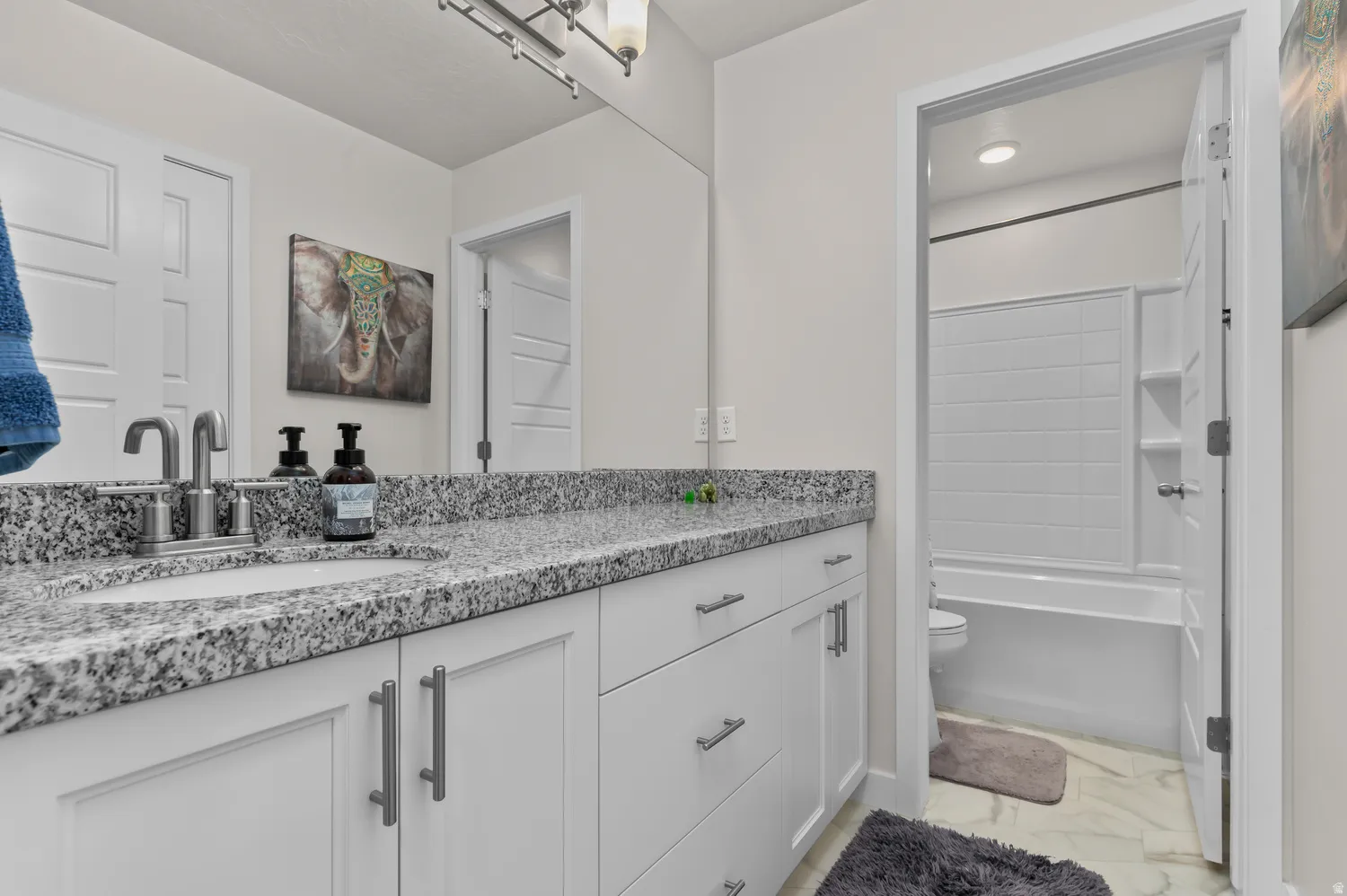 Spacious vanity featuring a granite-finish countertop, single undermount sink, and brushed nickel faucet