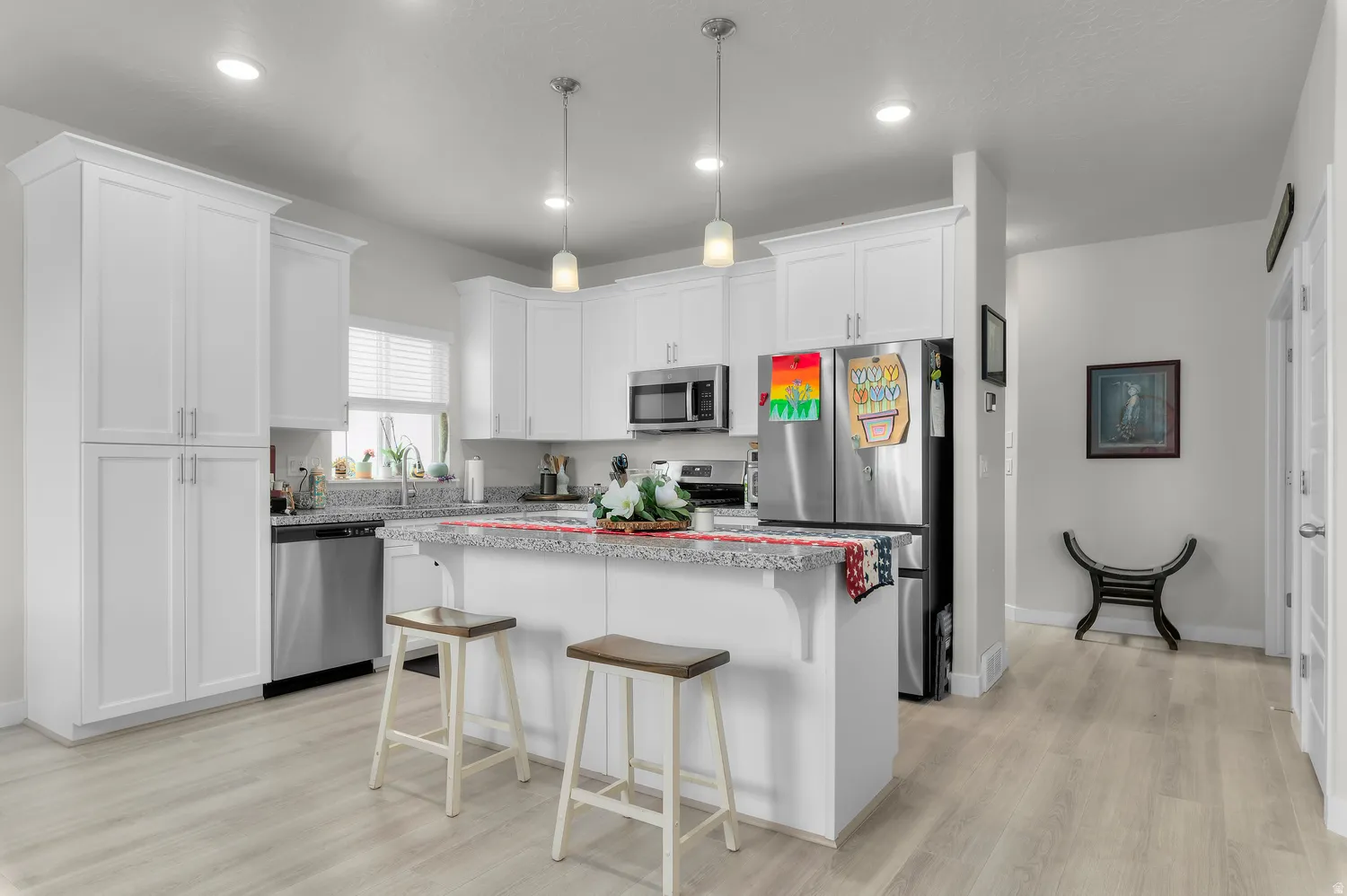 Modern kitchen featuring white cabinetry, stainless steel appliances, and a central island with a light-toned countertop