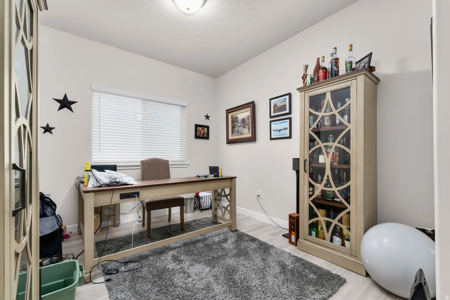 Light-filled room featuring wood-finish flooring, a contemporary ceiling light fixture, and a window with blinds