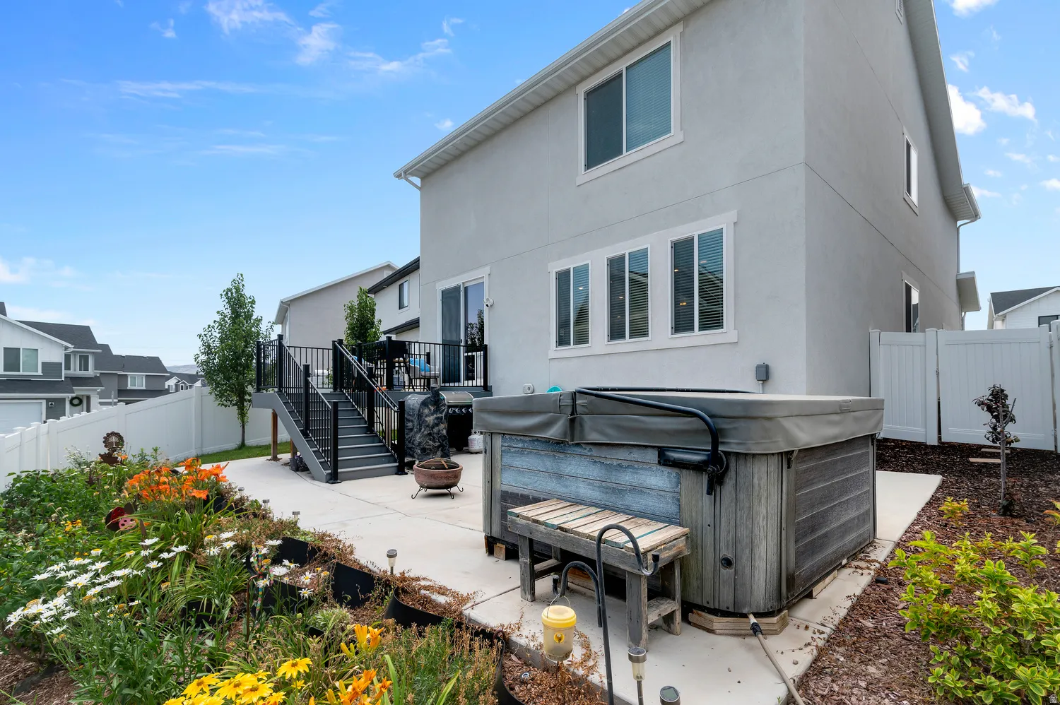 Rear patio featuring a hot tub, concrete pad, and multi-level deck with black railings