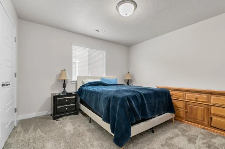 Carpeted room featuring a window with blinds, white paneled door, and a flush mount ceiling light fixture