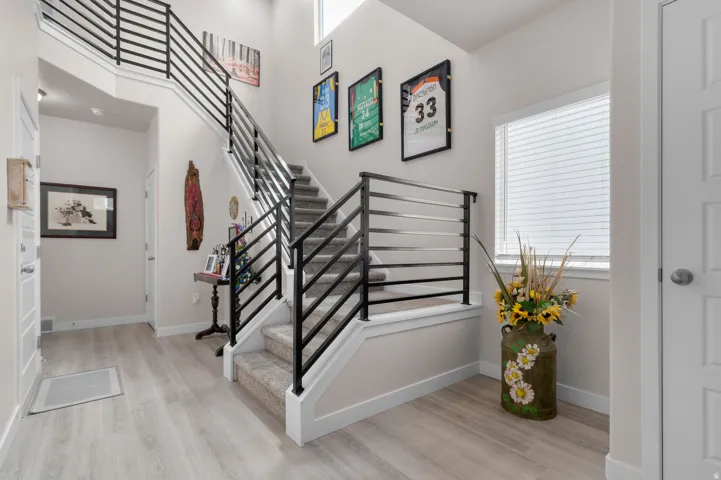 Two-story entryway featuring modern horizontal metal railings and light wood-finish flooring