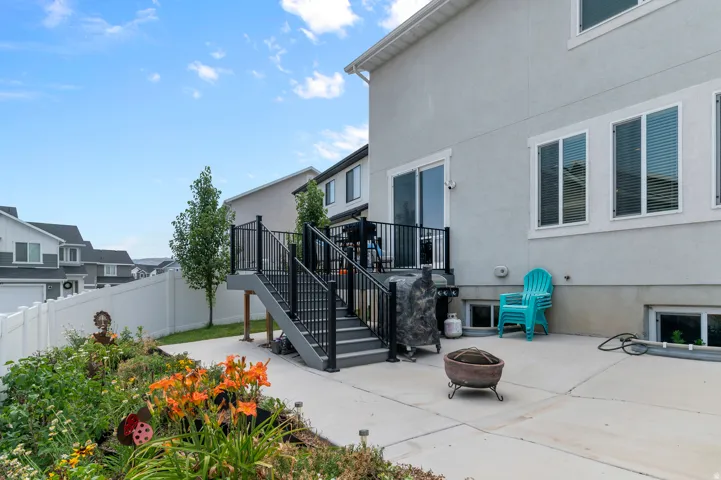 Outdoor patio space featuring a multi-level deck with black railings, a concrete patio, and garden landscaping