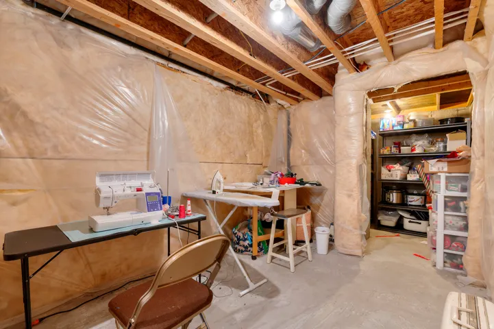 Unfinished basement space featuring exposed wood joists and concrete flooring