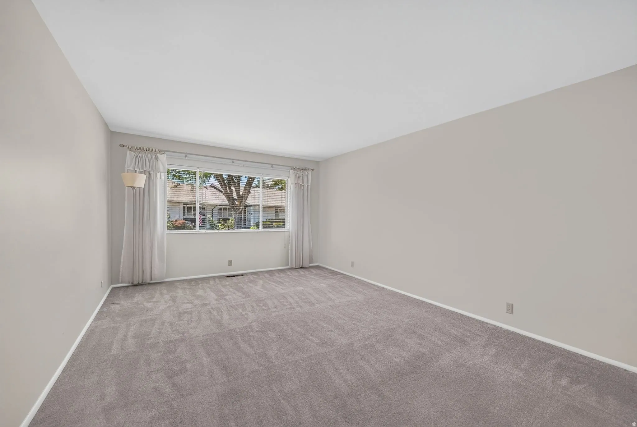 Spacious interior room with light neutral walls and gray carpeting