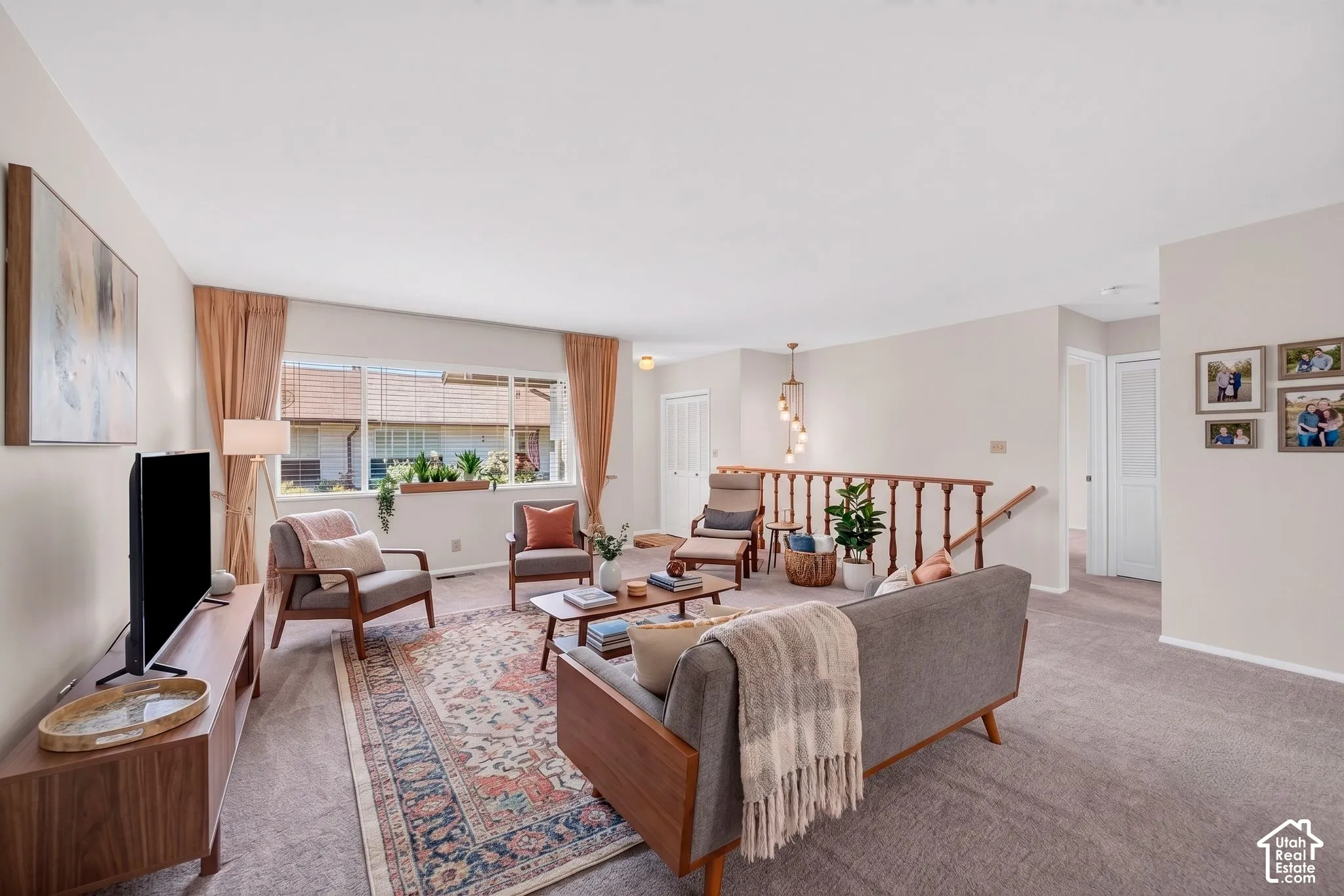 Spacious living area featuring neutral carpeting, a large picture window, and a wood railing staircase