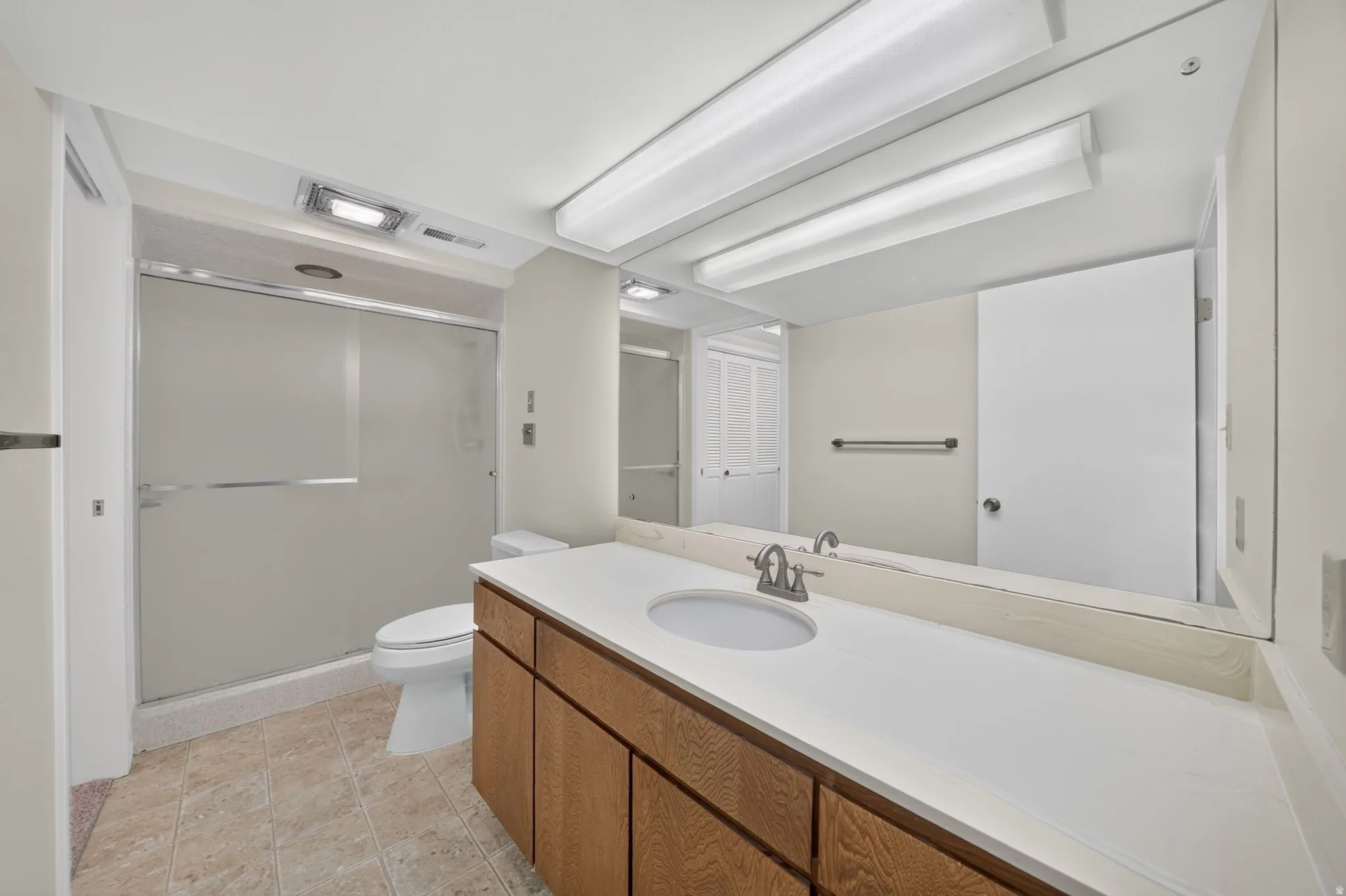 Bathroom with extended vanity featuring a white countertop and wood-finish cabinetry