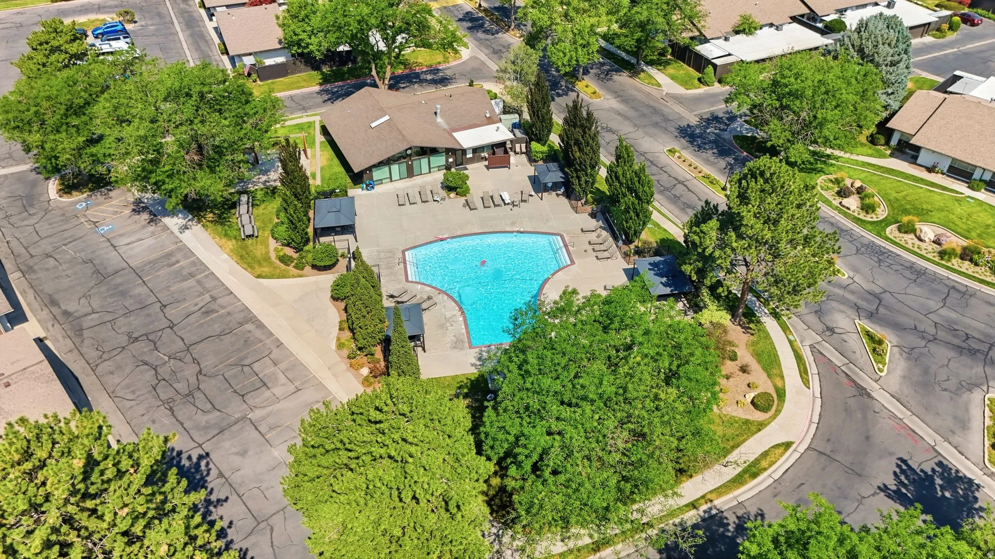 Resort-style pool with expansive surrounding hardscaping, sun loungers, and shaded seating areas