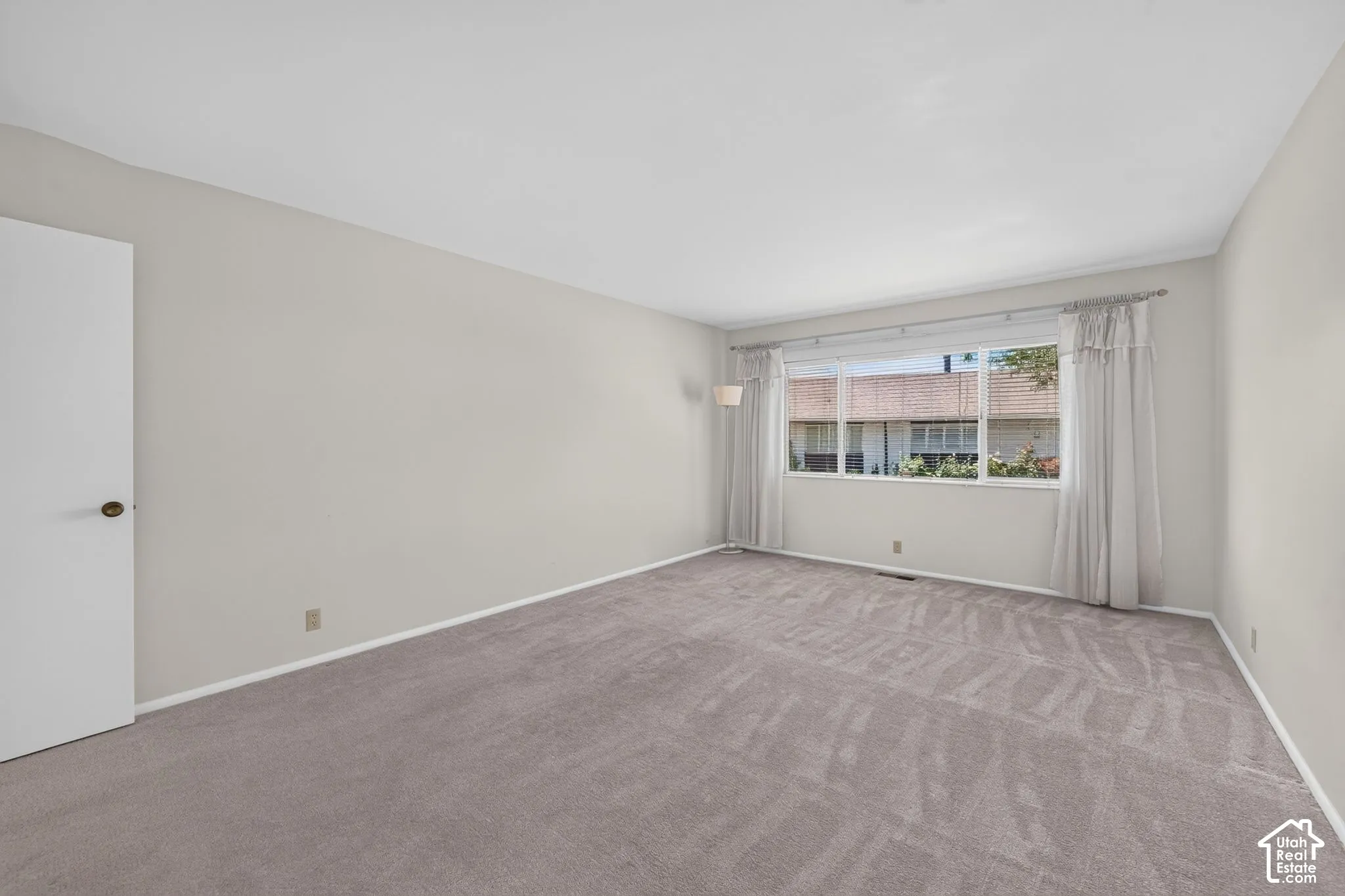 Spacious room featuring light gray carpeting and white baseboards