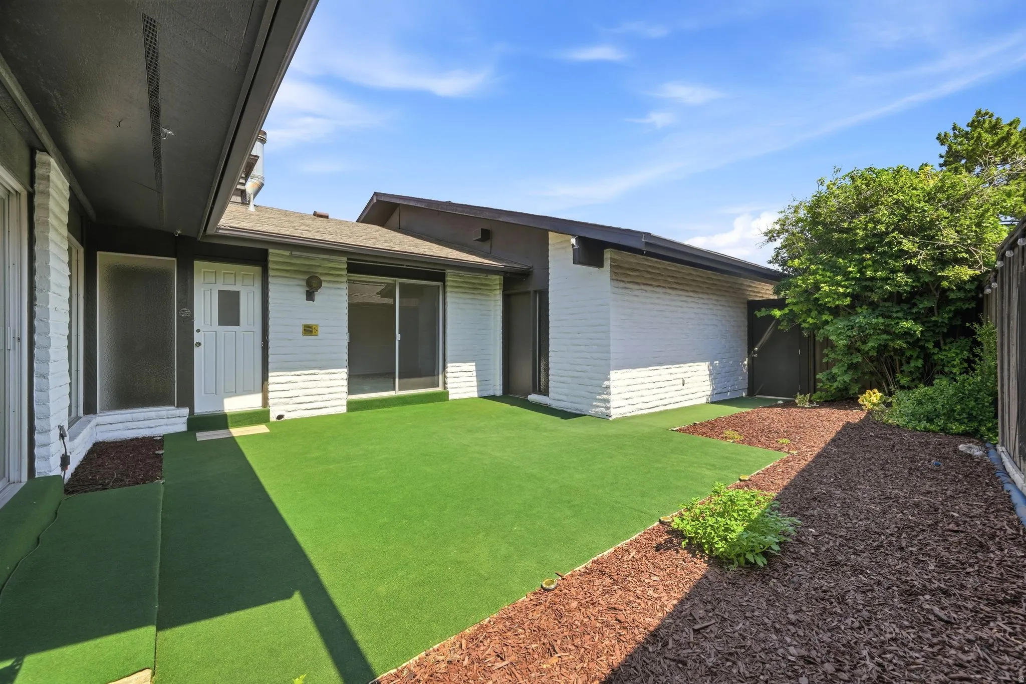 Private courtyard featuring artificial turf and wood chip landscaping