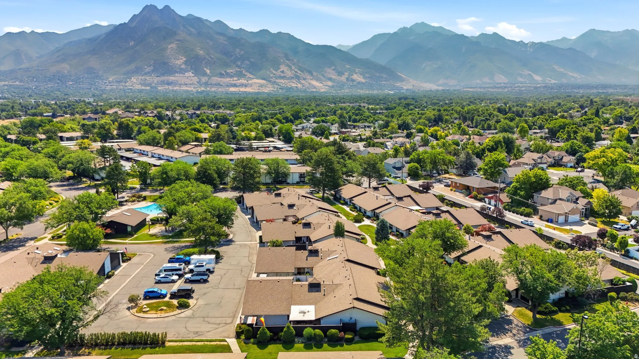 Expansive community with varied architectural styles, mature trees, and mountain scenery
