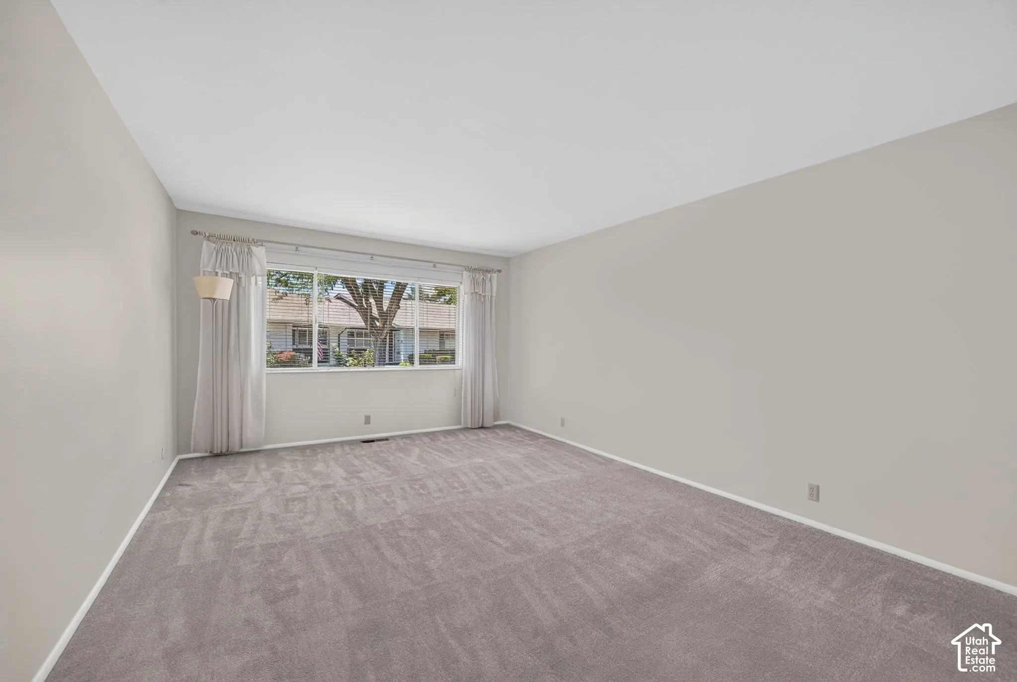 Spacious interior room with light neutral walls and gray carpeting