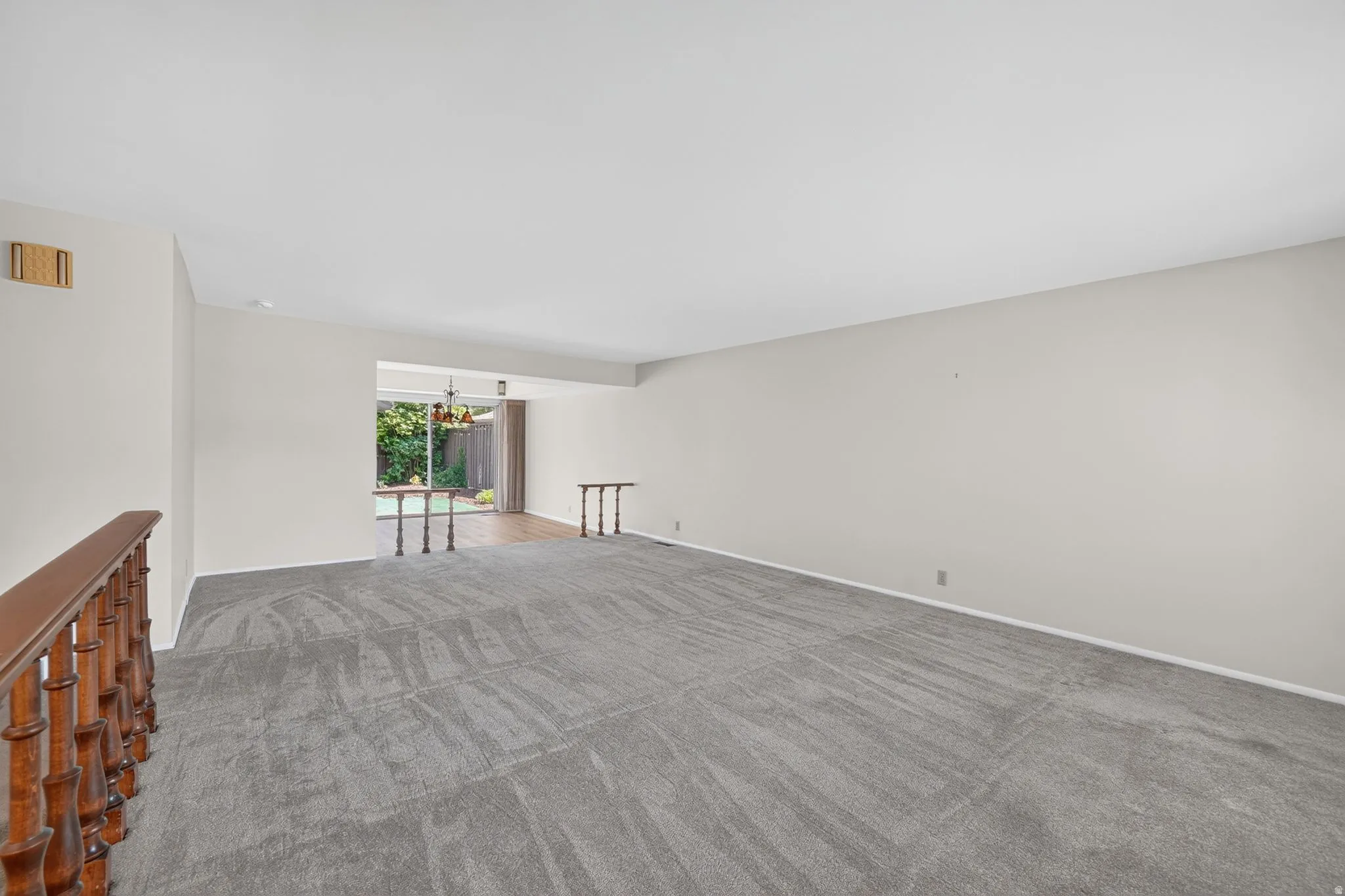 Spacious interior featuring neutral wall tones and updated gray carpet