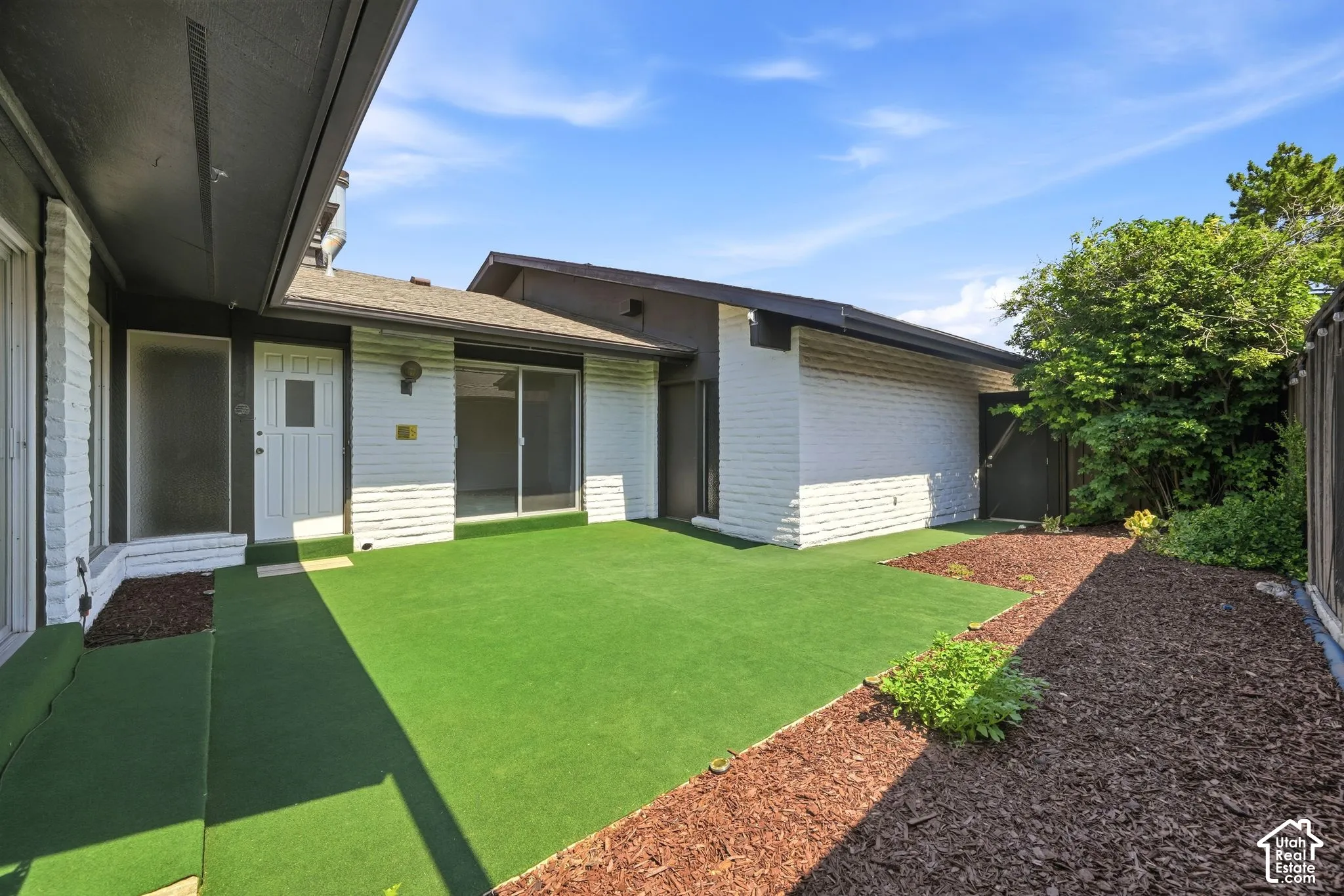 Private courtyard featuring artificial turf and wood chip landscaping