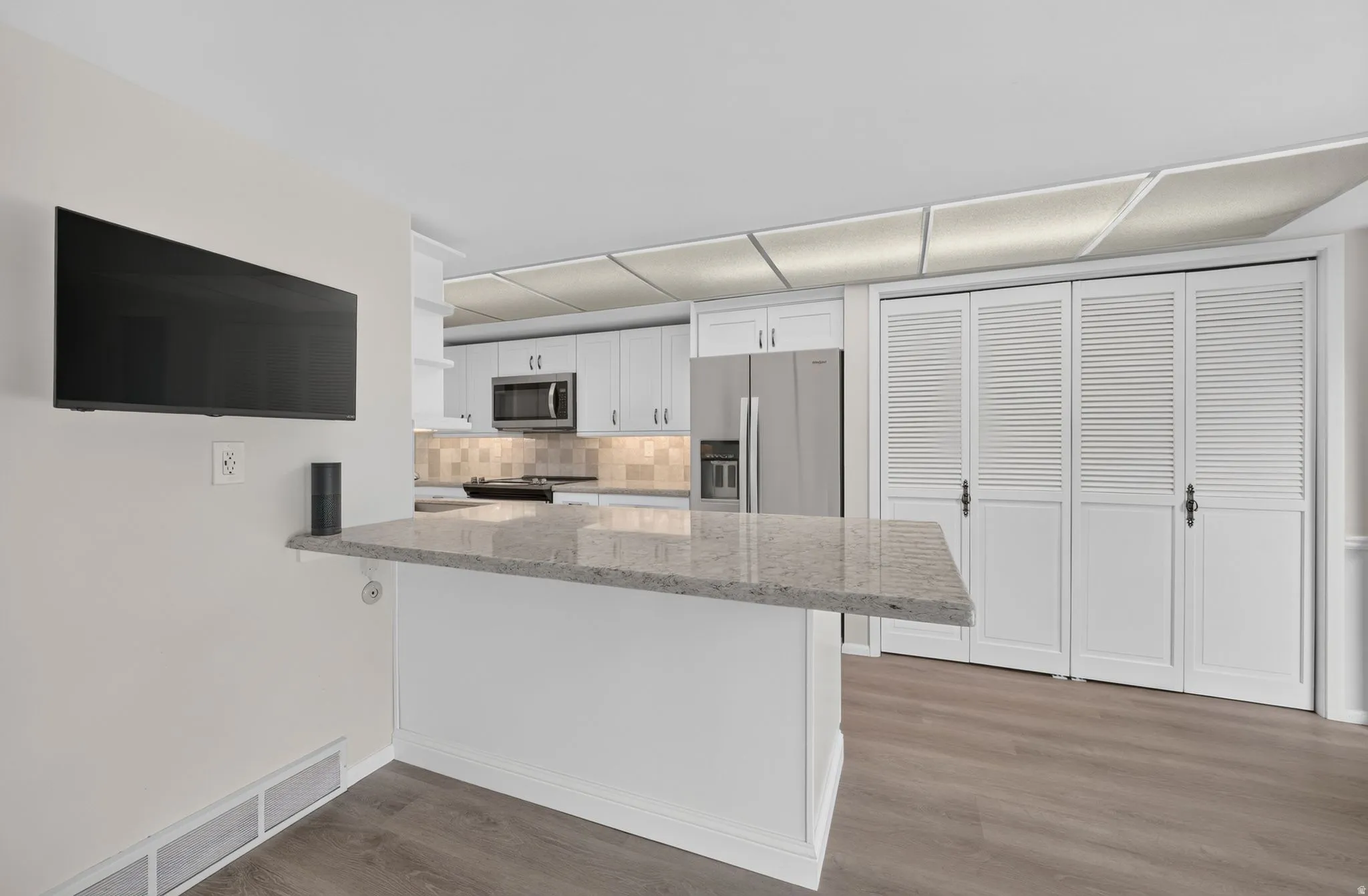 Kitchen featuring white cabinetry, stone-finish countertops, stainless steel appliances, and a tiled backsplash