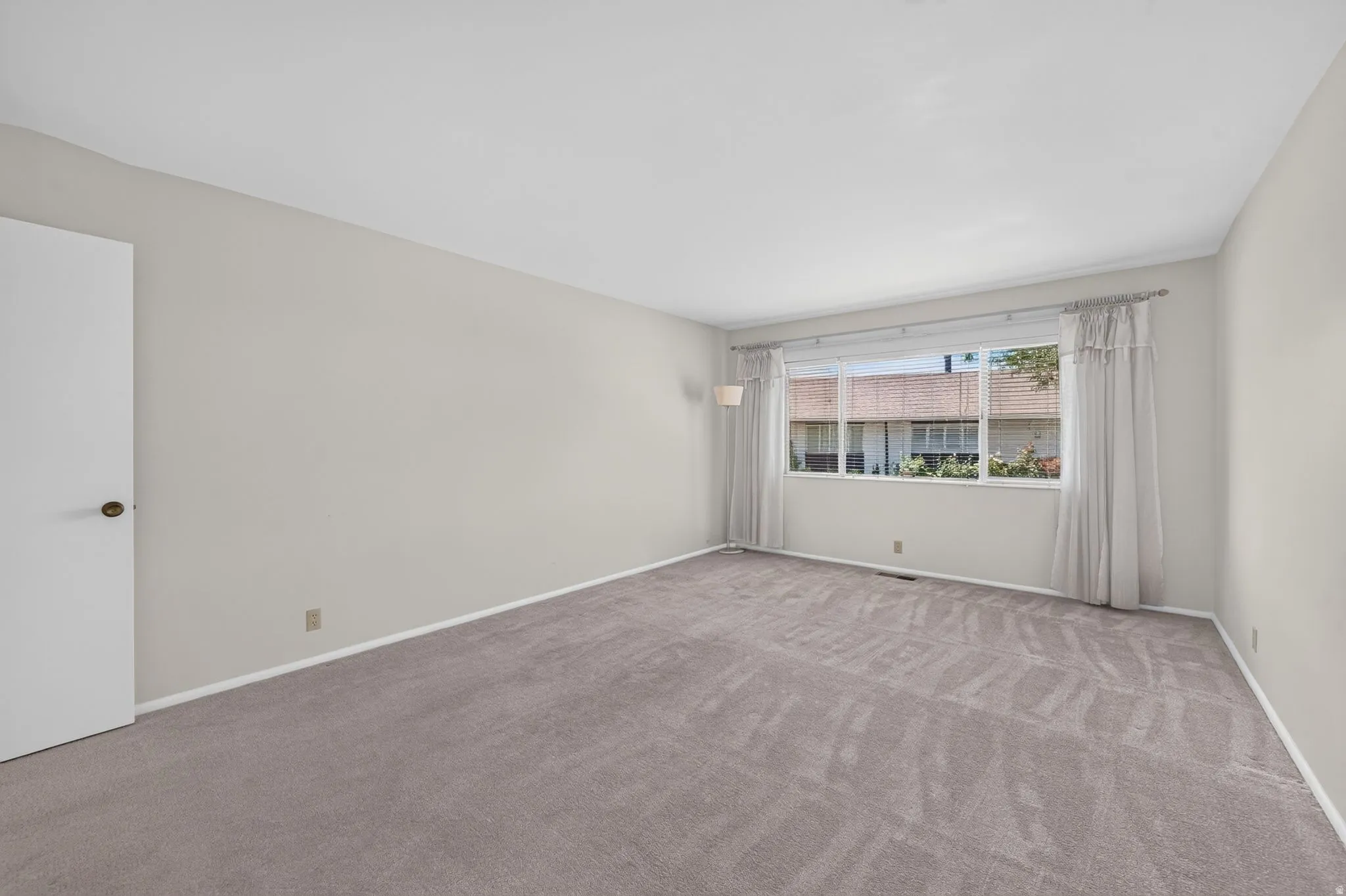 Spacious room featuring light gray carpeting and white baseboards