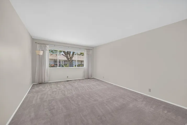 Spacious interior room with light neutral walls and gray carpeting