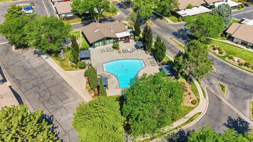 Resort-style pool with expansive surrounding hardscaping, sun loungers, and shaded seating areas