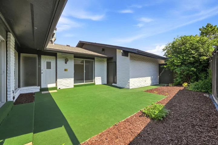 Private courtyard featuring artificial turf and wood chip landscaping