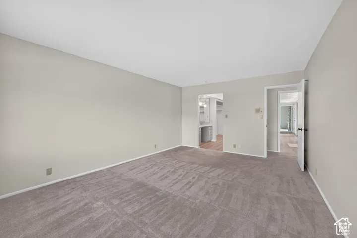 Spacious room featuring neutral carpeting, light-toned walls, and white trim