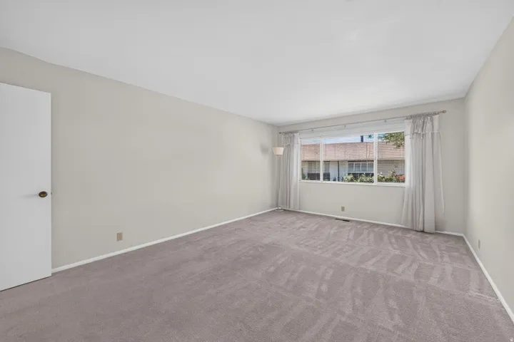 Spacious room featuring light gray carpeting and white baseboards