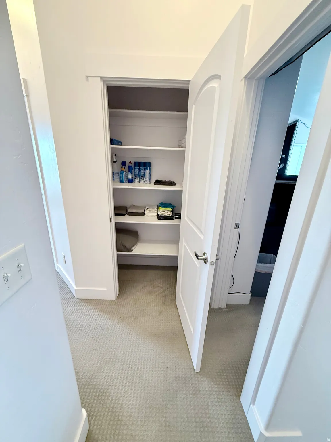 Recessed hall closet with multiple white shelving units