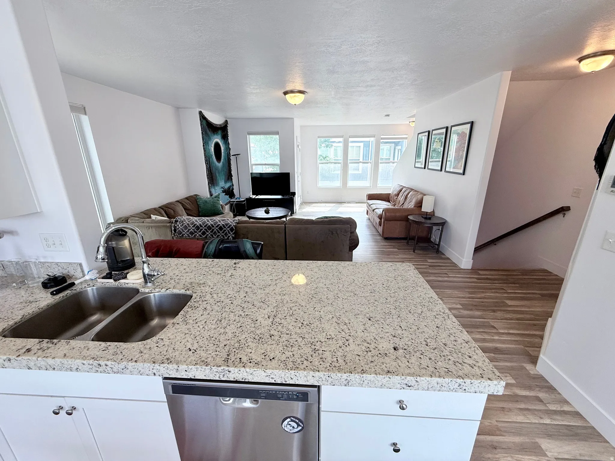Kitchen featuring granite countertops, a double basin sink with a gooseneck faucet, and white cabinetry