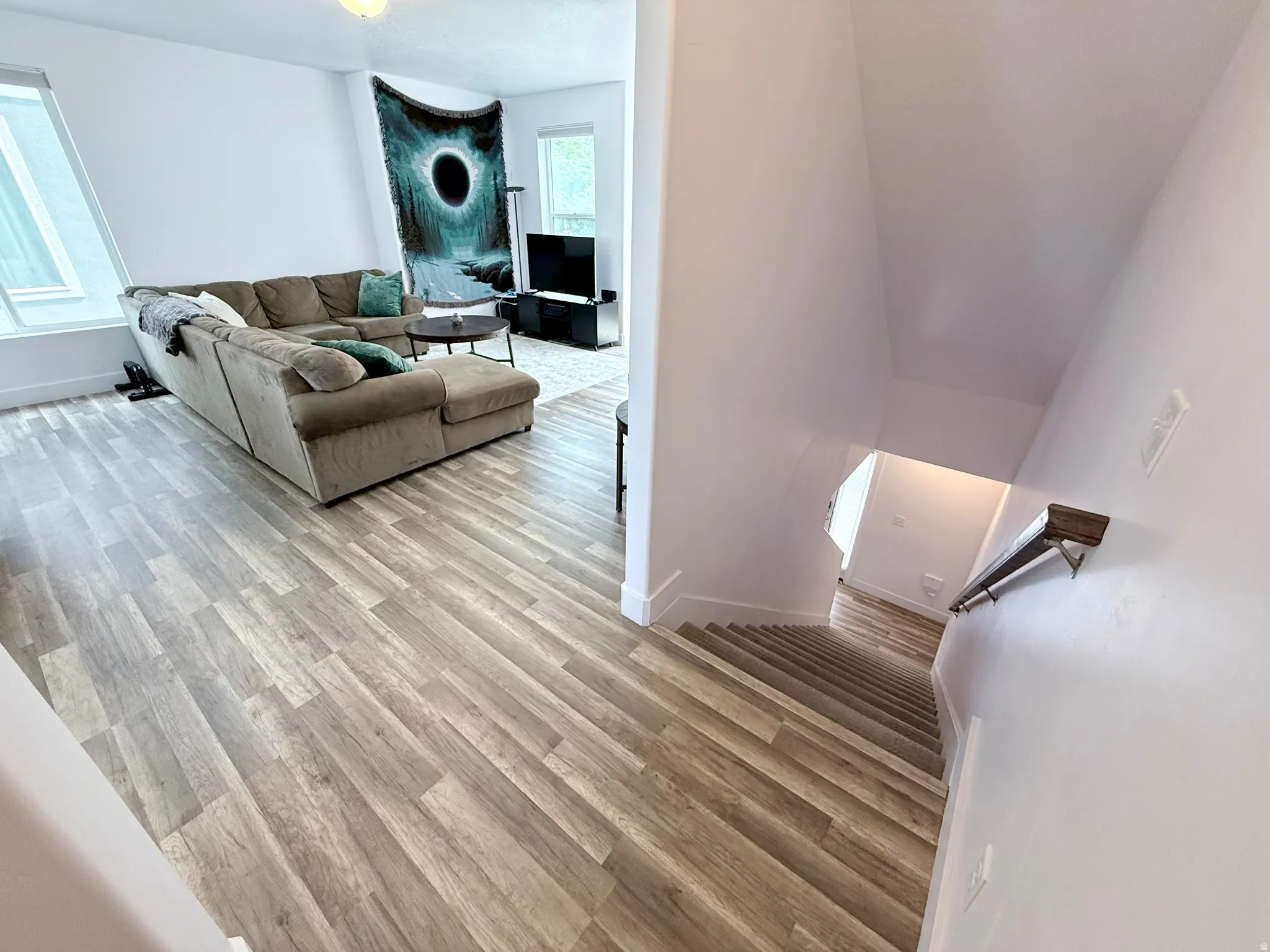 Open concept living area with wood-finish flooring, white walls, and a prominent window