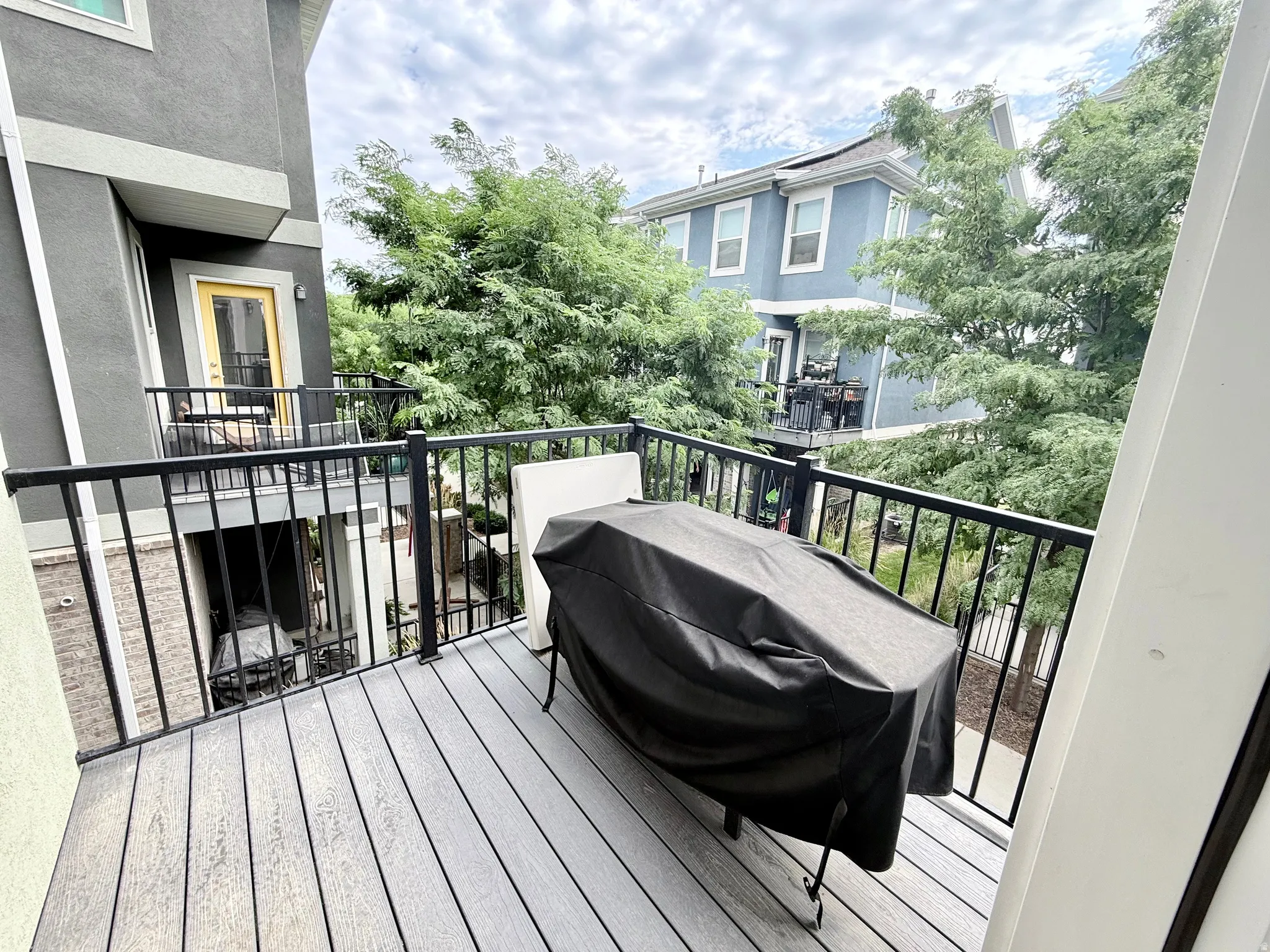 Outdoor balcony deck featuring composite decking and black metal railings.