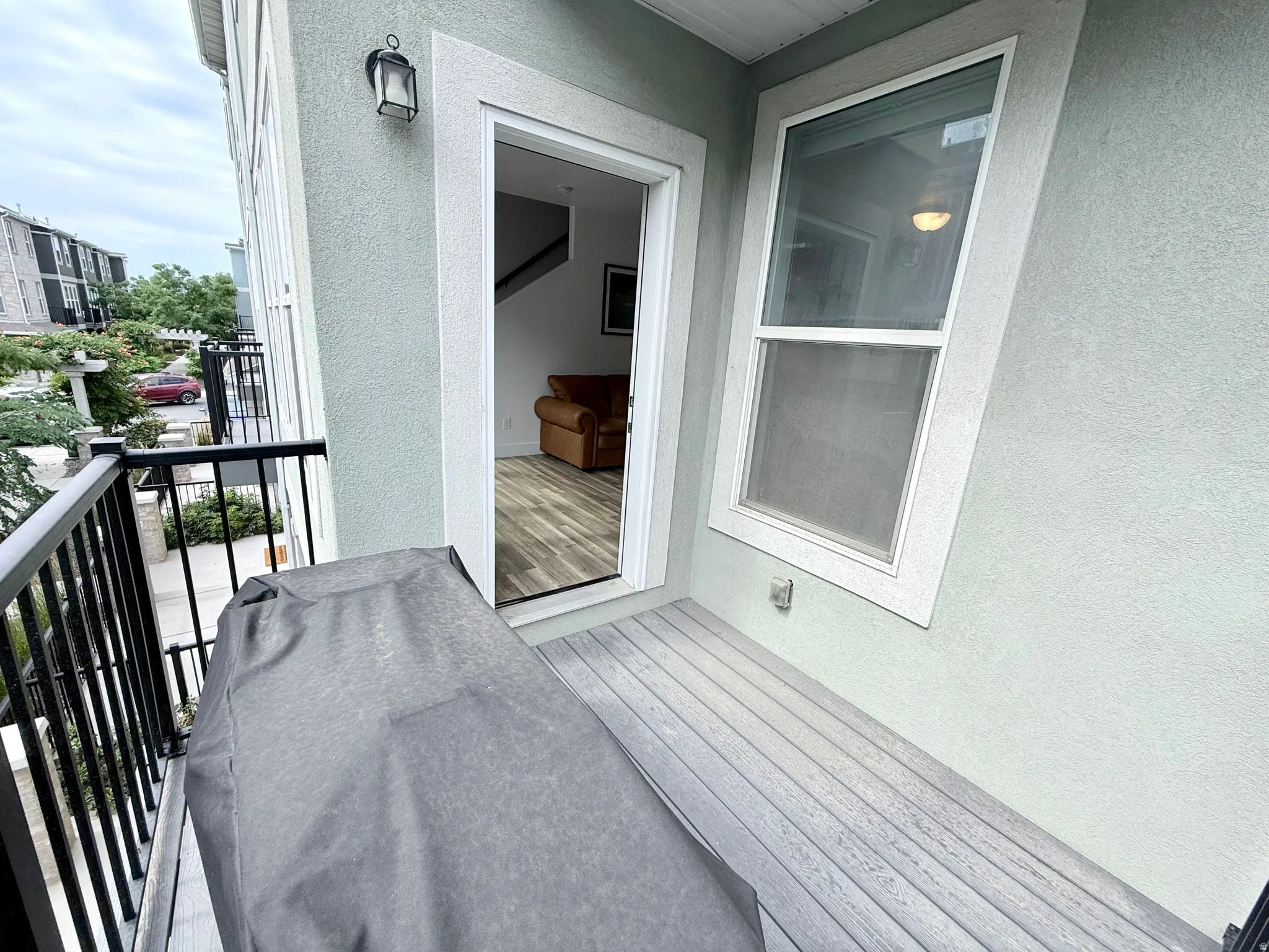 Private balcony deck with composite decking, black metal railings, and stucco siding